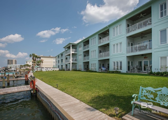 view of dock featuring a balcony, a water view, and a yard