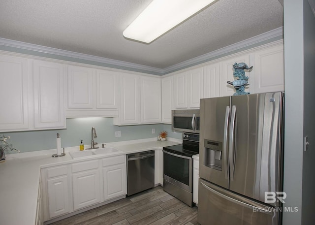 kitchen featuring appliances with stainless steel finishes, white cabinets, crown molding, and sink