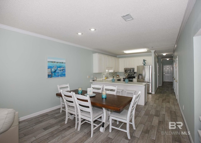 dining space with sink, a textured ceiling, dark hardwood / wood-style flooring, and ornamental molding