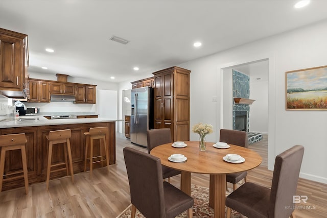 dining area featuring a fireplace, light wood-style flooring, visible vents, and recessed lighting