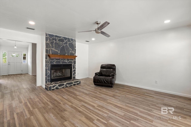 unfurnished living room featuring wood finished floors, visible vents, a fireplace, ceiling fan, and baseboards