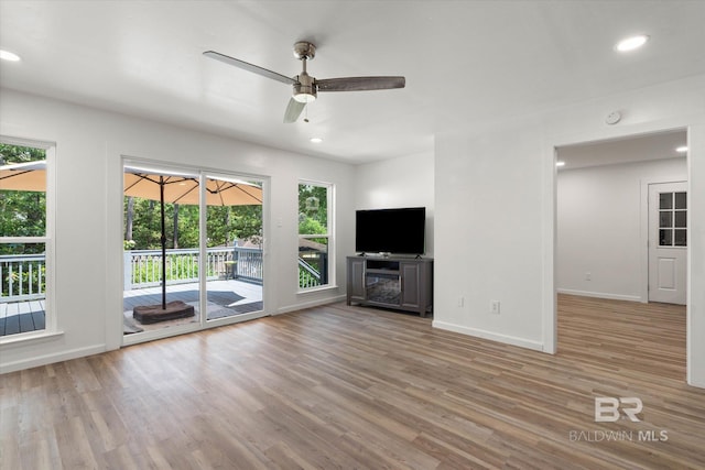 unfurnished living room with baseboards, plenty of natural light, and wood finished floors