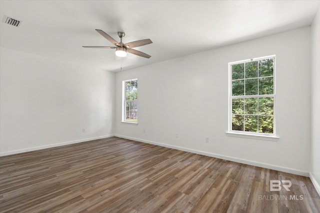 spare room with a wealth of natural light, visible vents, baseboards, and ceiling fan