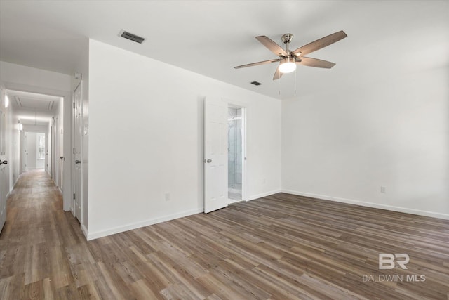 unfurnished room featuring a ceiling fan, attic access, baseboards, visible vents, and wood finished floors