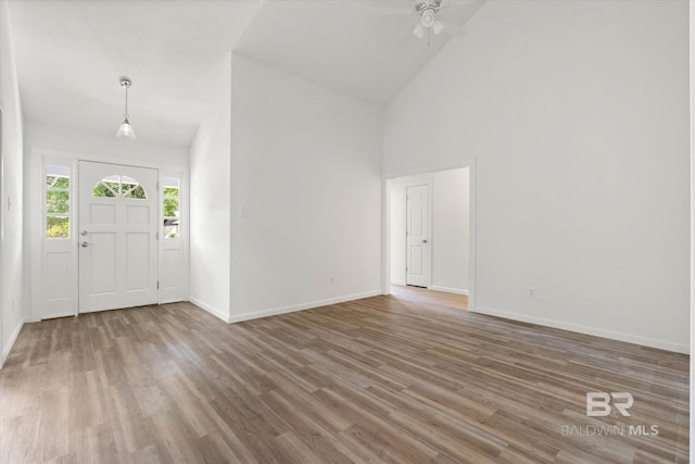 entryway featuring baseboards, ceiling fan, high vaulted ceiling, and wood finished floors
