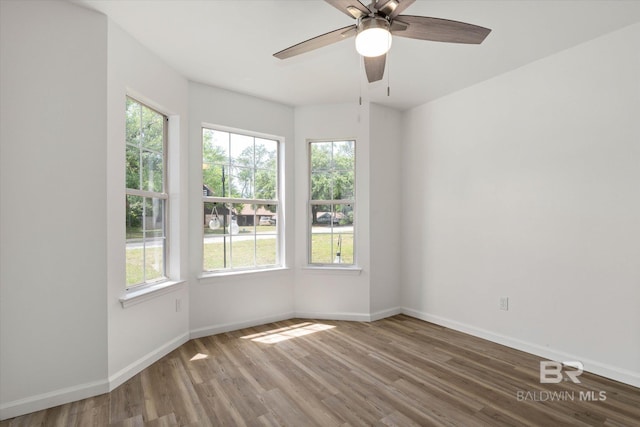 unfurnished room with baseboards, a healthy amount of sunlight, and wood finished floors