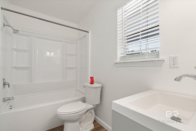 full bath with toilet, wood finished floors, a sink, baseboards, and shower / bathtub combination