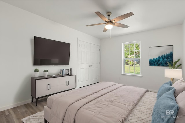 bedroom featuring a closet, wood finished floors, baseboards, and ceiling fan