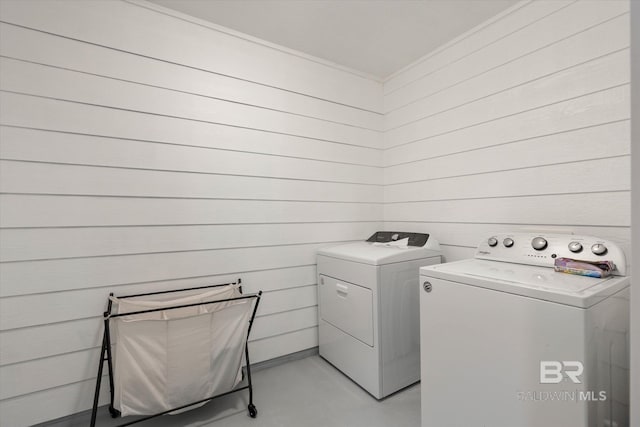 washroom featuring laundry area, wooden walls, and separate washer and dryer