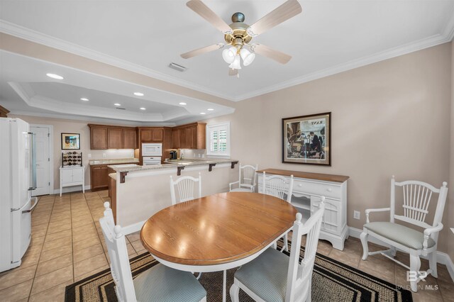 dining space with crown molding, baseboards, a raised ceiling, ceiling fan, and visible vents