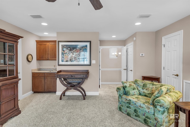 office space with a sink, light carpet, baseboards, visible vents, and ceiling fan