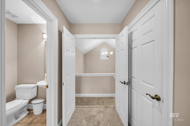 half bath featuring visible vents, baseboards, toilet, tile patterned floors, and lofted ceiling