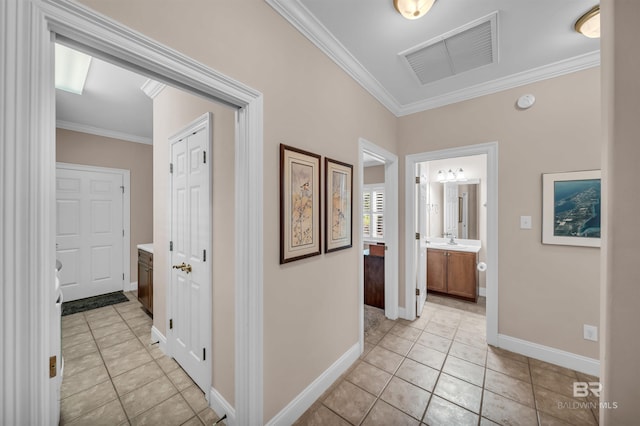 hall featuring baseboards, visible vents, crown molding, and light tile patterned floors