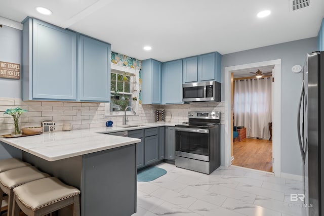 kitchen featuring blue cabinets, a sink, visible vents, marble finish floor, and appliances with stainless steel finishes