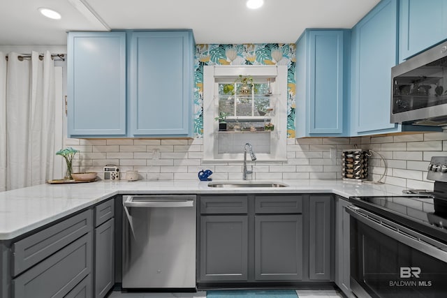 kitchen with blue cabinets, appliances with stainless steel finishes, gray cabinets, and a sink