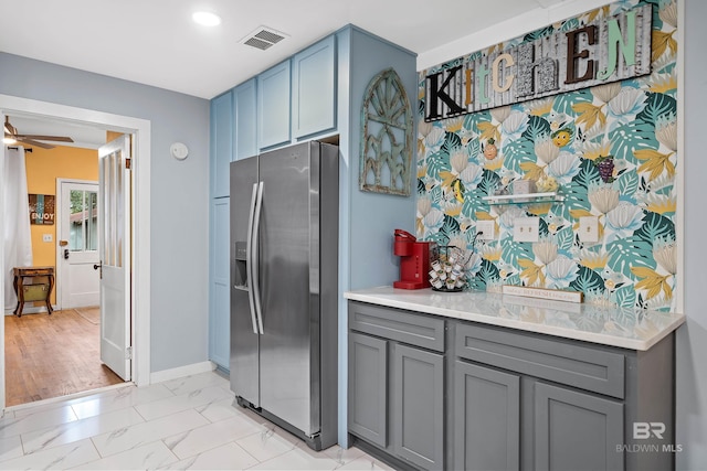 kitchen with marble finish floor, visible vents, gray cabinetry, and stainless steel fridge with ice dispenser