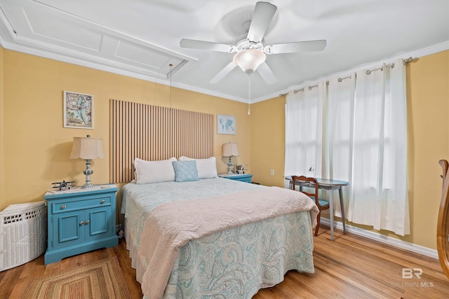 bedroom with ceiling fan, ornamental molding, wood finished floors, and attic access