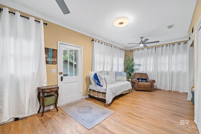 living area with crown molding, visible vents, ceiling fan, and light wood finished floors