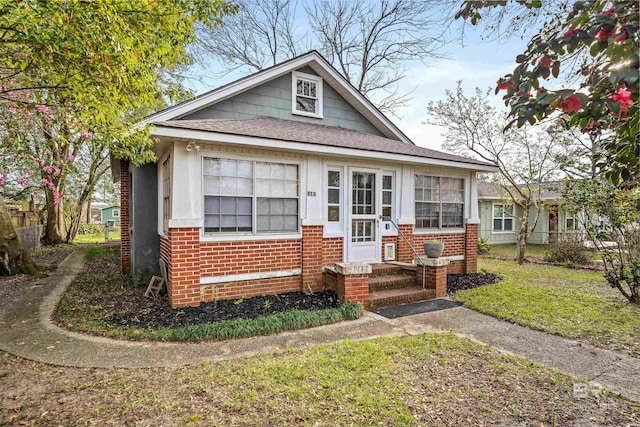 bungalow featuring brick siding, a front lawn, a shingled roof, and fence