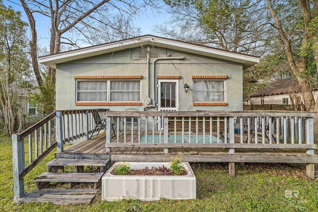 rear view of house with a wooden deck and stucco siding