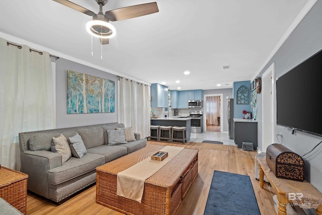 living area with light wood-type flooring, ornamental molding, a ceiling fan, and recessed lighting