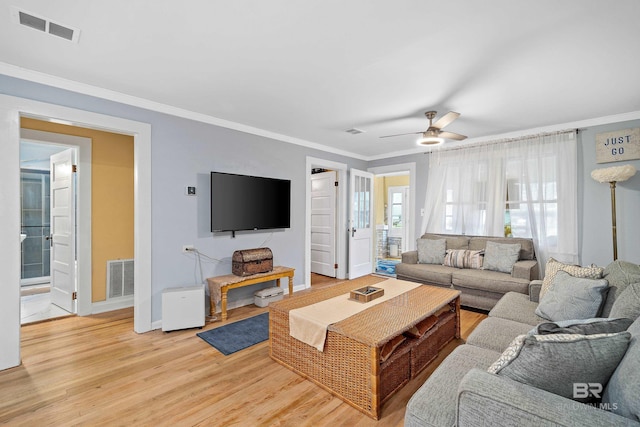 living area featuring ornamental molding, light wood-type flooring, visible vents, and baseboards