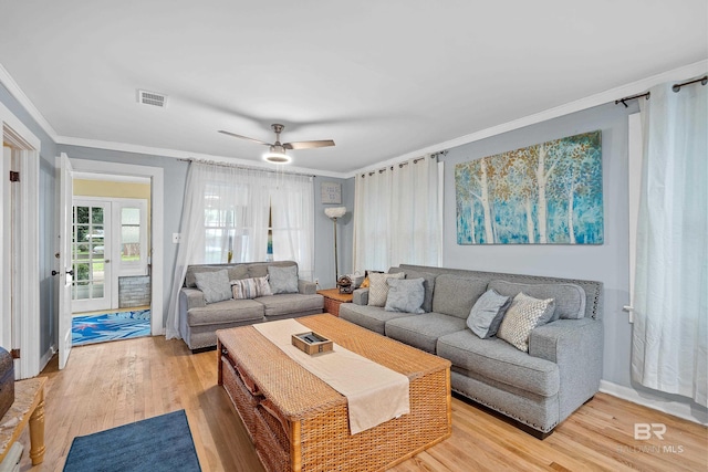 living room with ornamental molding, visible vents, ceiling fan, and light wood-style flooring