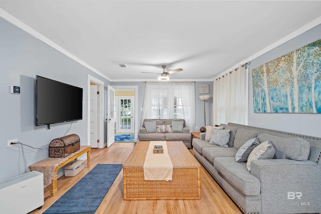 living area featuring ceiling fan, ornamental molding, wood finished floors, and visible vents