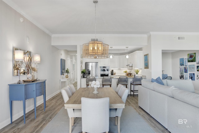 dining space featuring visible vents, crown molding, light wood-type flooring, and baseboards