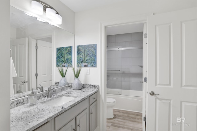 bathroom with vanity, toilet, wood finished floors, and bath / shower combo with glass door