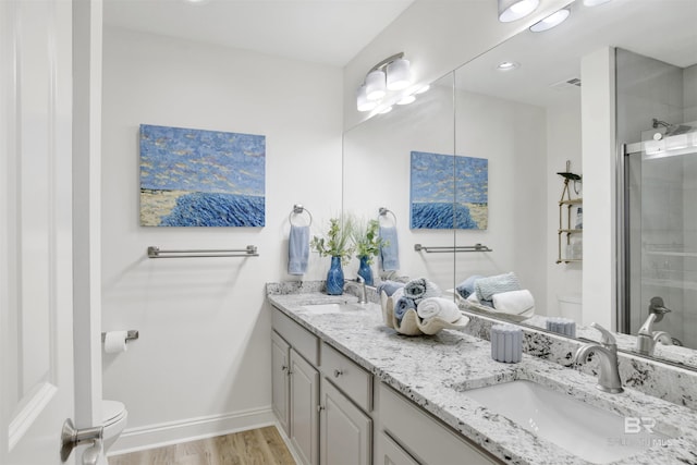 bathroom featuring wood finished floors, a shower stall, toilet, and a sink