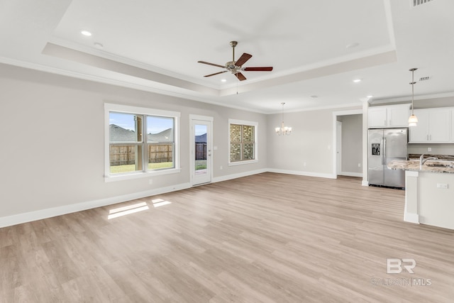 unfurnished living room with light wood finished floors and a tray ceiling