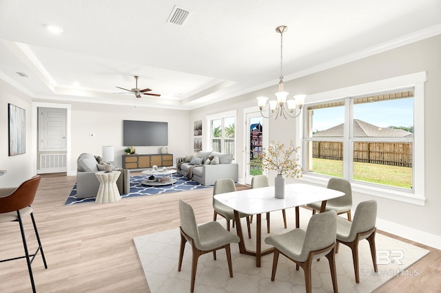 dining room featuring a tray ceiling, light wood-style floors, visible vents, and a healthy amount of sunlight