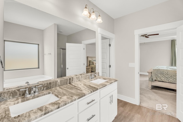 ensuite bathroom featuring baseboards, connected bathroom, a sink, and wood finished floors