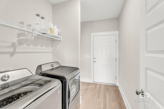 washroom featuring light wood-style floors, laundry area, baseboards, and separate washer and dryer