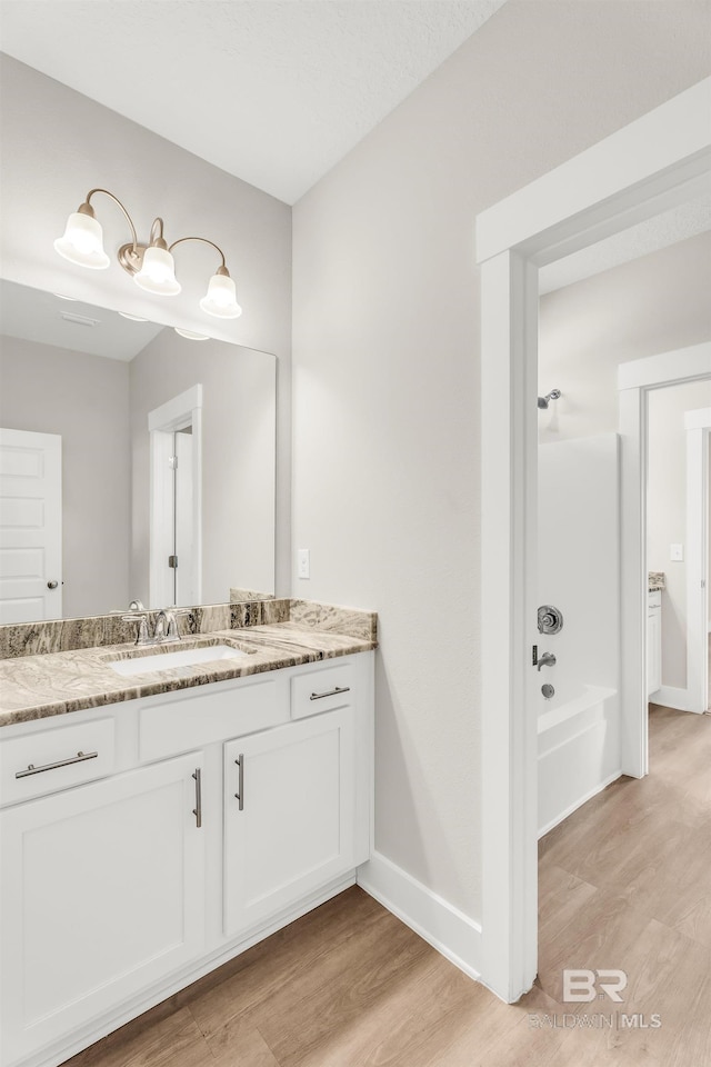 bathroom with baseboards, wood finished floors, and vanity