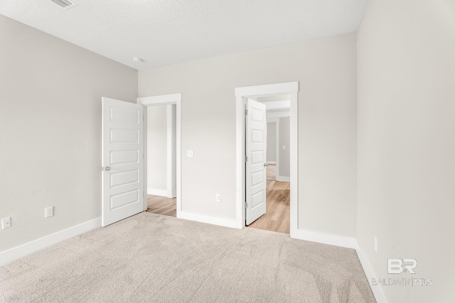 unfurnished bedroom featuring light carpet and baseboards