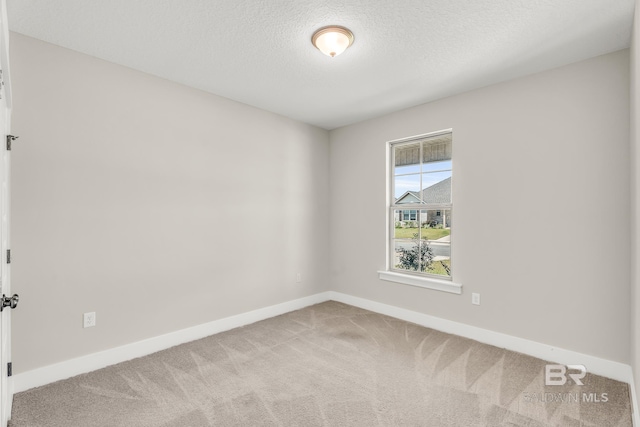 carpeted spare room featuring baseboards and a textured ceiling