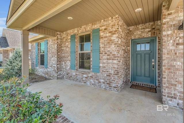 entrance to property featuring a patio and brick siding