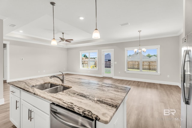 kitchen featuring open floor plan, light stone counters, a sink, and white cabinets