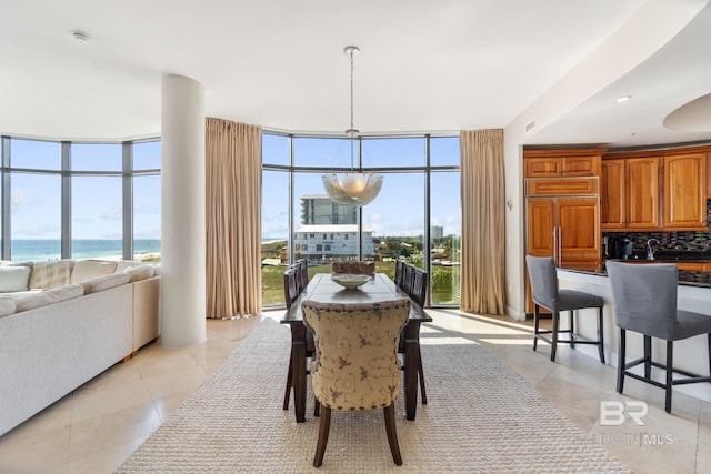 dining room featuring expansive windows, light tile patterned floors, plenty of natural light, and a water view