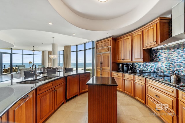 kitchen featuring wall chimney exhaust hood, dark stone countertops, a sink, black electric stovetop, and backsplash