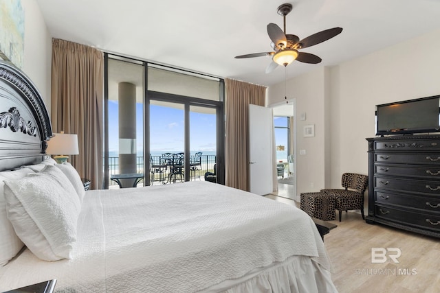 bedroom with access to outside, ceiling fan, expansive windows, and wood finished floors