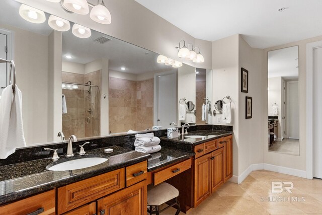 bathroom with double vanity, a stall shower, baseboards, and a sink