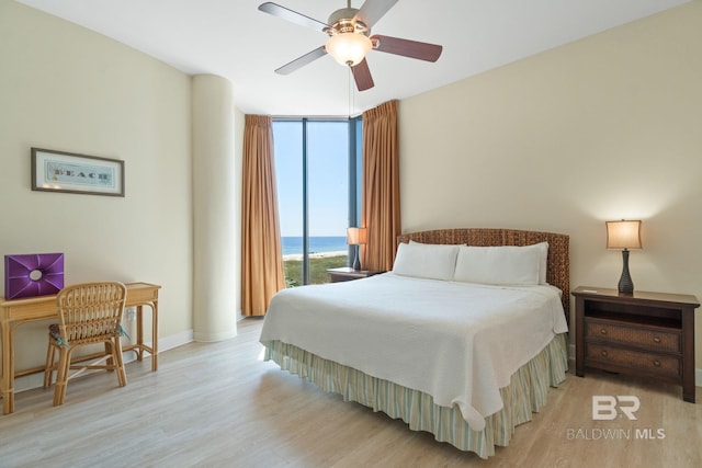 bedroom featuring ceiling fan, a wall of windows, light wood-type flooring, and baseboards