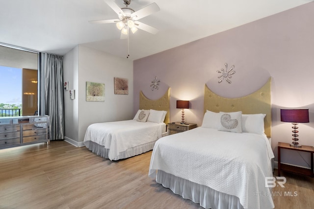 bedroom with a ceiling fan, light wood-style flooring, and baseboards