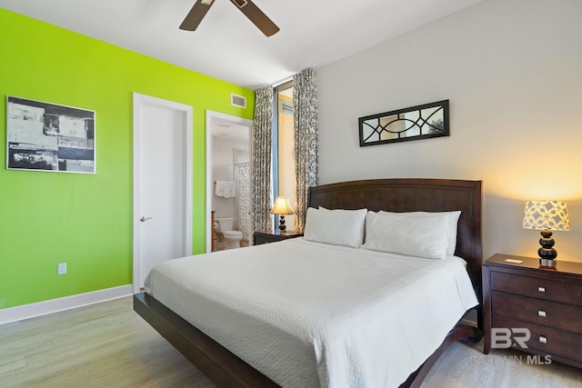 bedroom featuring baseboards, visible vents, a ceiling fan, wood finished floors, and ensuite bathroom