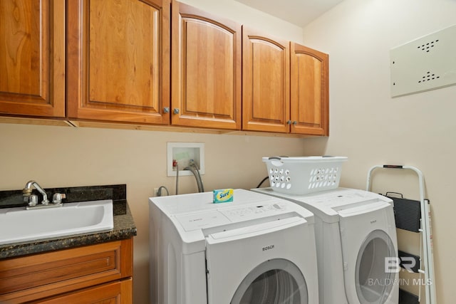 laundry area featuring washing machine and dryer, cabinet space, and a sink