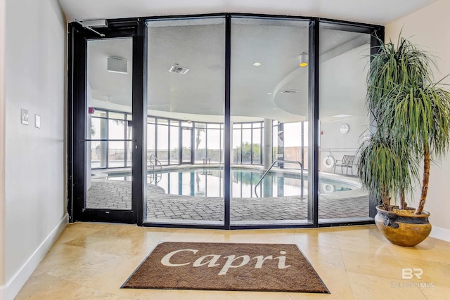 doorway with expansive windows, visible vents, and baseboards