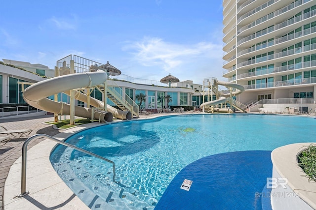 community pool with a water slide and a patio area